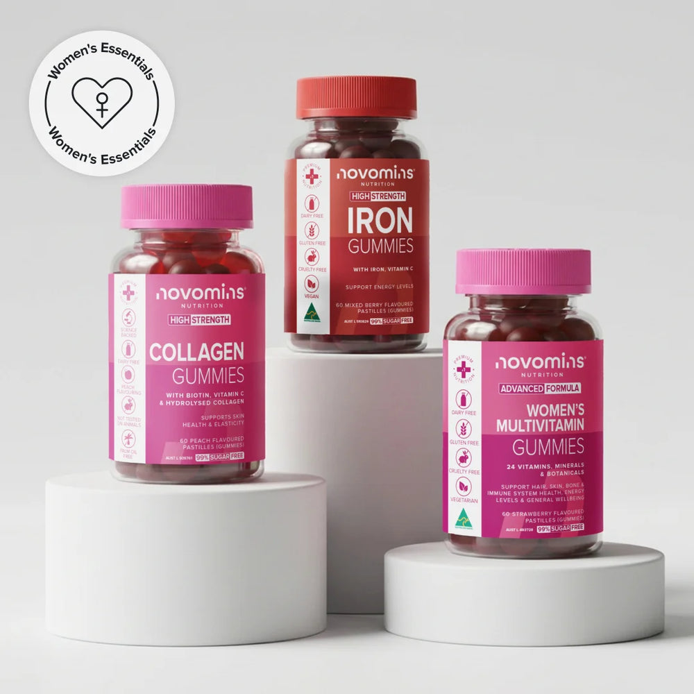 Three supplement bottles from novomins arranged on white cylindrical pedestals against a black background. The bottles are labeled Collagen Gummies, Iron Gummies, and Women's Multivitamin Gummies, with pink, red, and magenta labels and red caps.