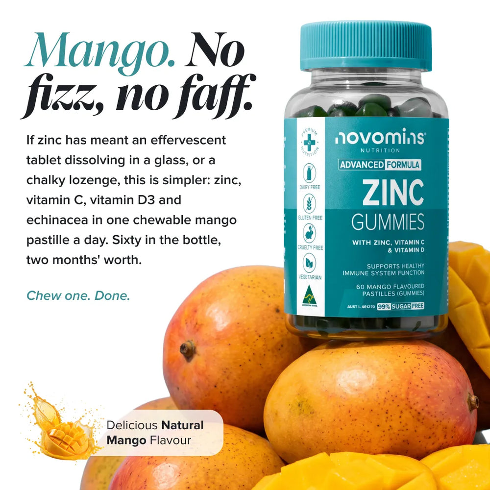 A bottle of novominis Nutrition Advanced Formula Zinc Gummies with a bright teal label and cap, set against a pile of fresh mangoes. The image includes promotional text highlighting the 'Mango.