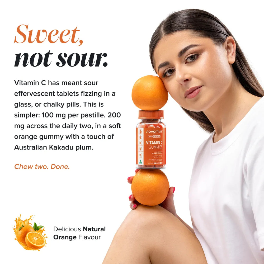 A woman in a white shirt holds a bottle of Vitamin C Gummies balanced on two oranges against a white background with promotional text reading 'Sweet, not sour.' and 'Delicious Natural Orange Flavour.