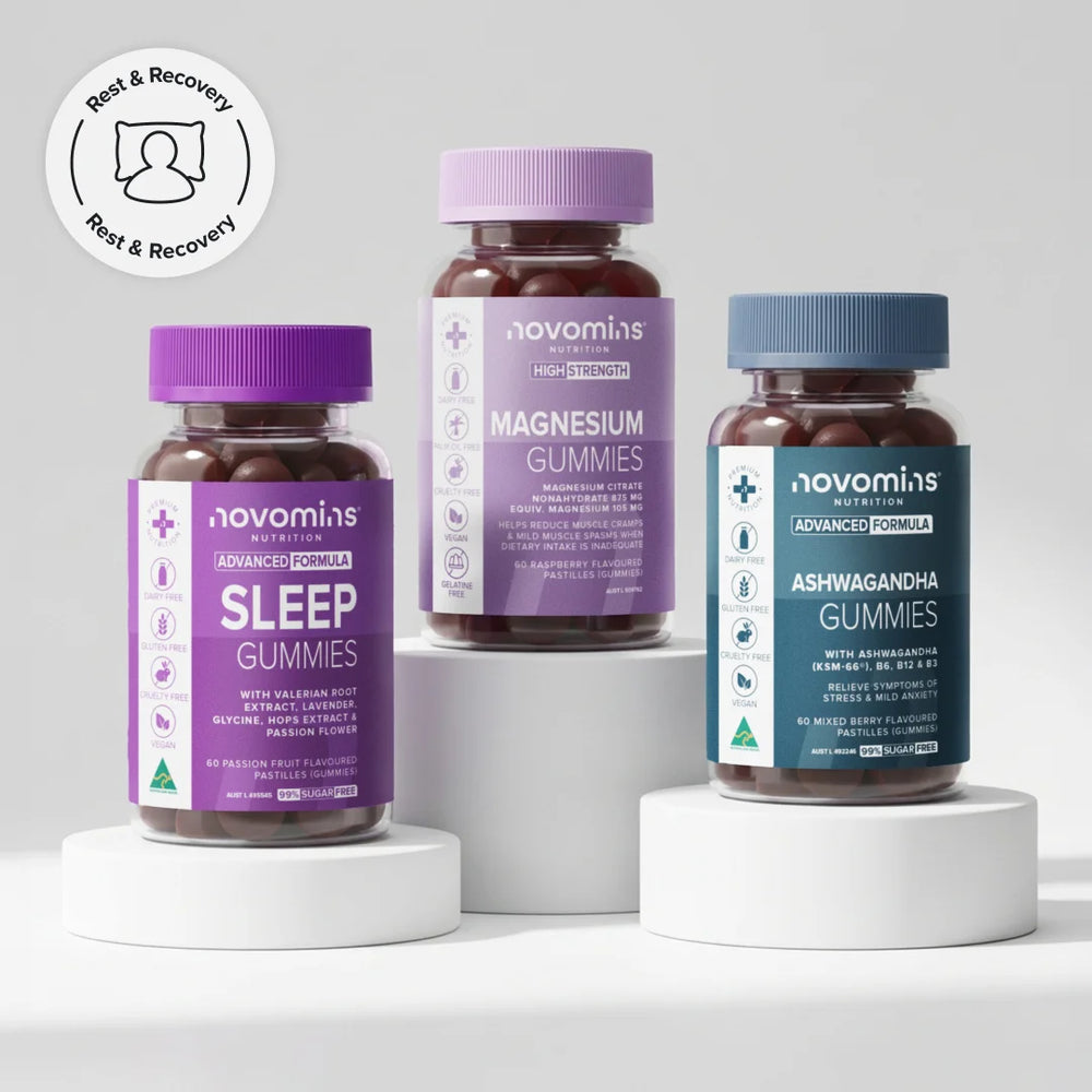 Three supplement bottles from novomins on white pedestals against a light gray background. The bottles are labeled Sleep Gummies, Magnesium Gummies, and Ashwagandha Gummies, with purple, lavender, and blue caps and labels.
